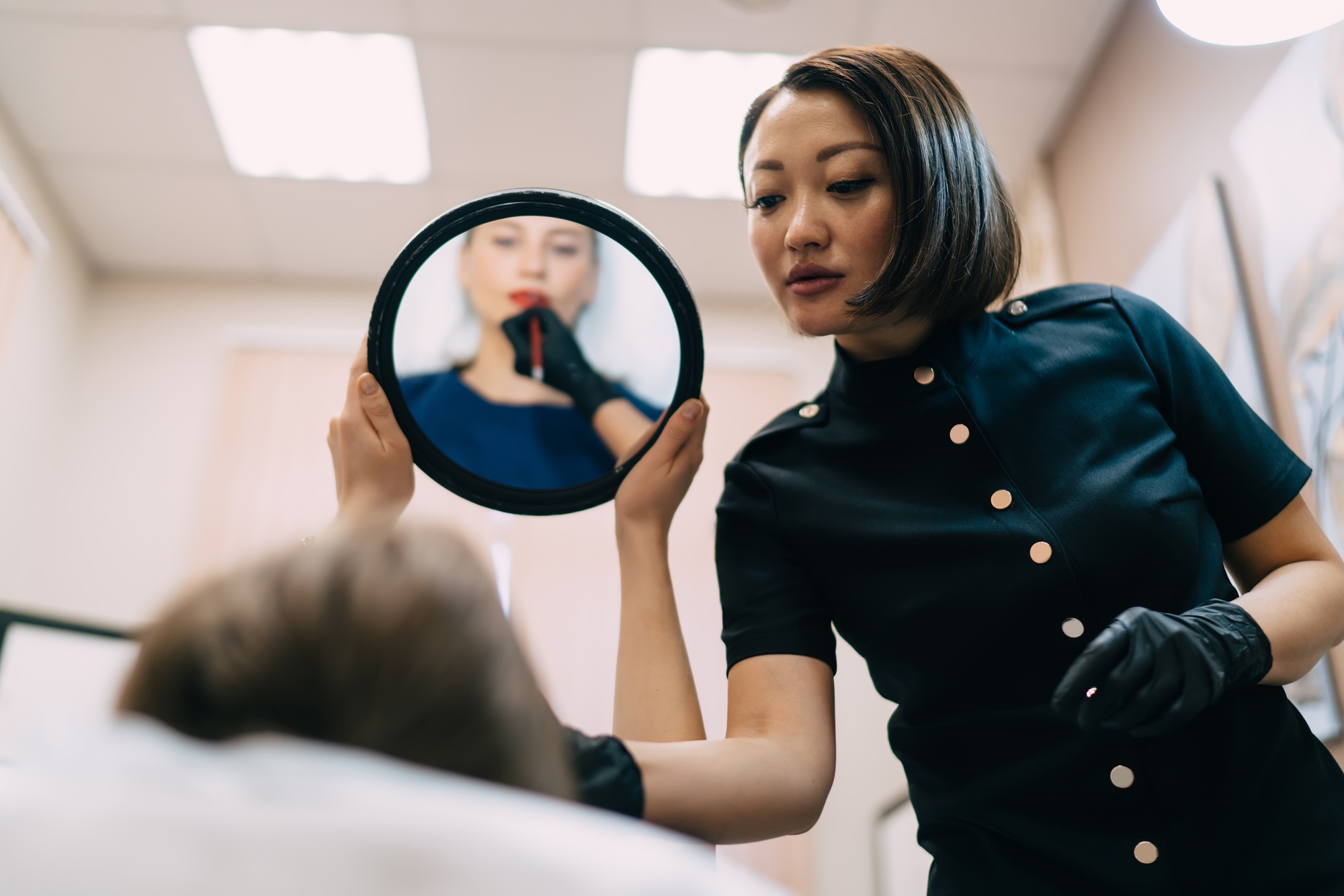 Girl looking at lips in mirror near beautician